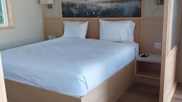Un dormitorio con una cama de madera, una mesita de noche, una lámpara de pared y un cuadro de paisaje grande.