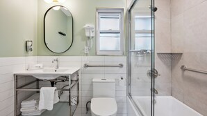 Une salle de bain moderne avec une douche à parois de verre, des toilettes blanches, un lavabo avec un miroir et un porte-serviettes.