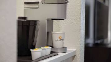 A coffee machine with a cup labeled "La Quinta" on a countertop.
