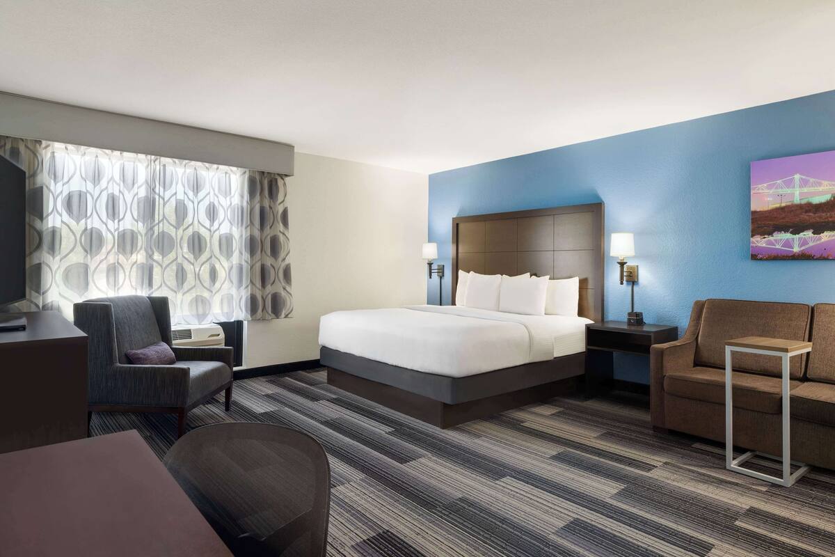 Ein Hotelzimmer mit einem großen Bett, einem Schreibtisch, einem Stuhl und einem Fernseher.