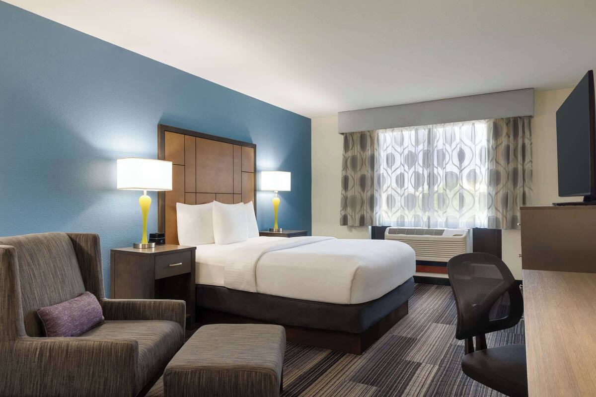 Ein Hotelzimmer mit einem großen Bett, zwei Nachttischlampen, einem Schreibtisch, einem Stuhl und einem Fernseher.