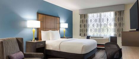 A hotel room with a large bed, two bedside lamps, a desk, a chair, and a TV.