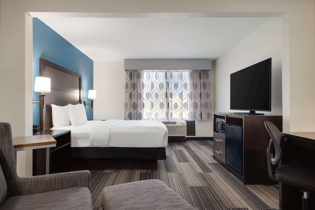 Ein Hotelzimmer mit Bett, Schreibtisch, Fernseher, Stuhl und Schlafsofa.