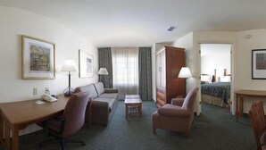 Une chambre d’hôtel comprenant un lit, un bureau, un canapé, une chaise, une commode et deux lampes.