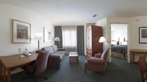 Ein Hotelzimmer mit einem Bett, einem Schreibtisch, einem Sofa, einem Sessel, einem Schminktisch und zwei Lampen.