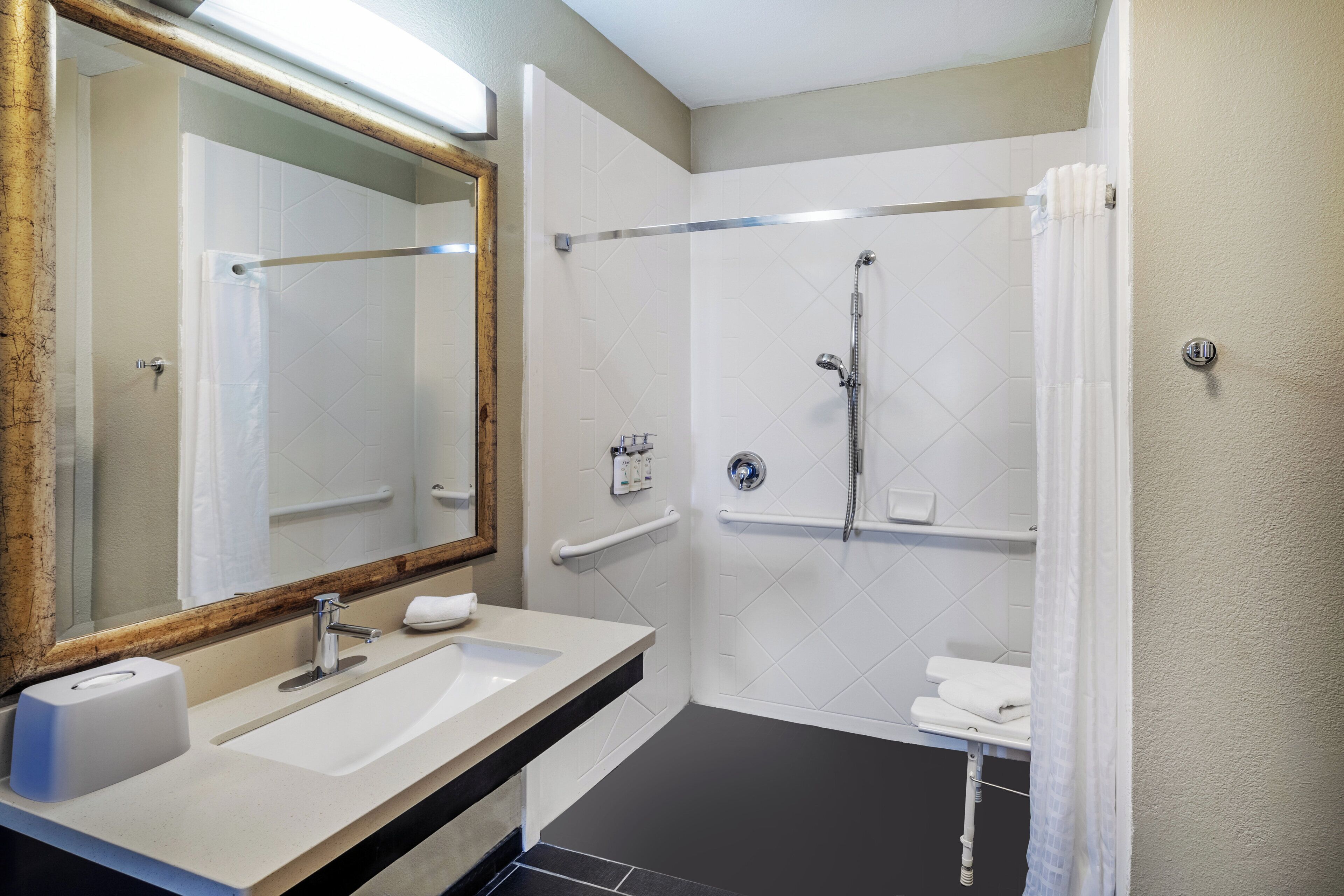 A bathroom with a sink, mirror, shower, and towel rack.