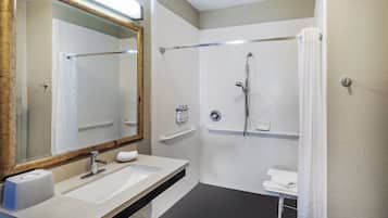 A bathroom with a sink, mirror, shower, and towel rack.