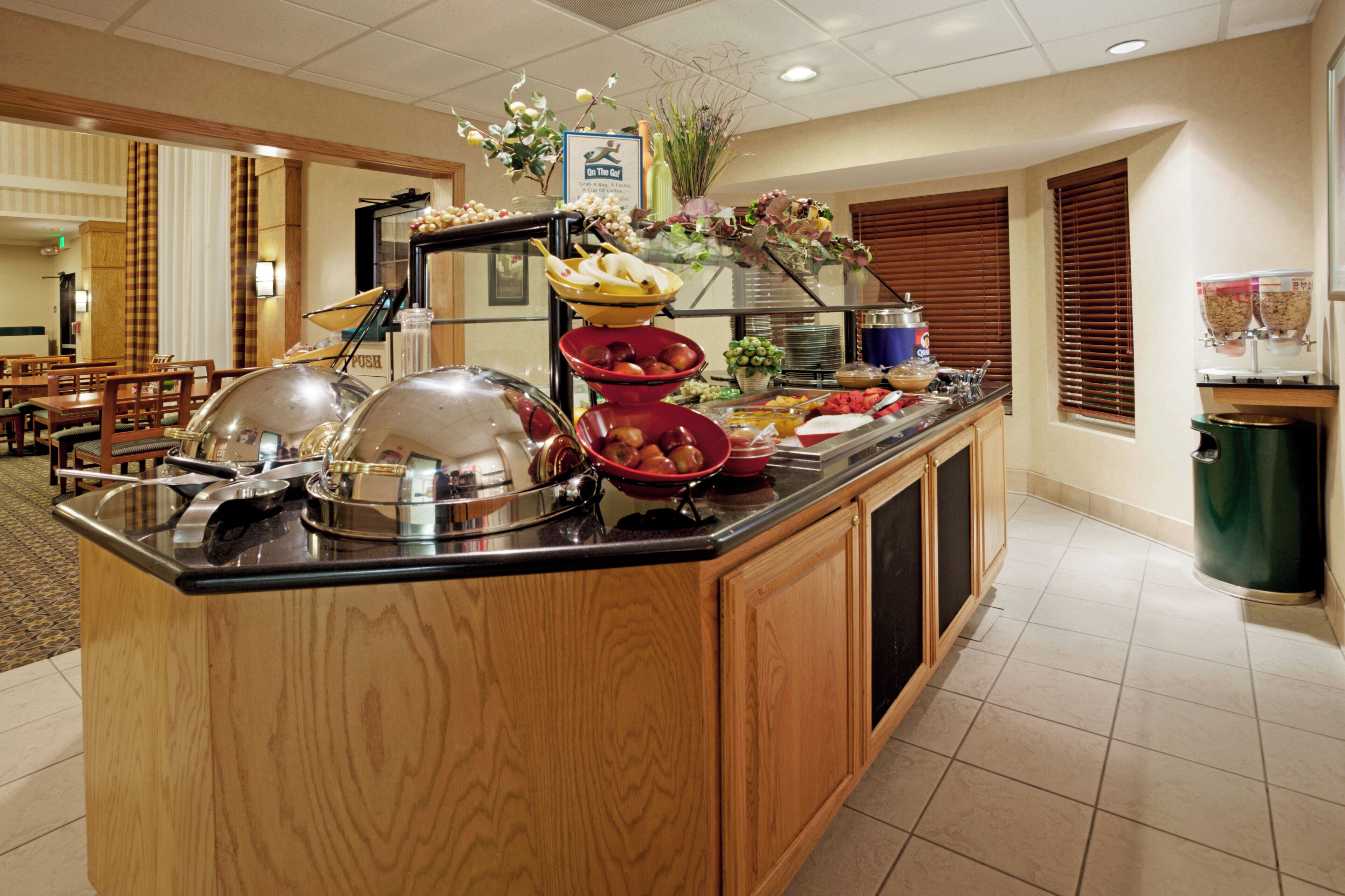 A buffet counter with various food items and a sign indicating a self-service option.
