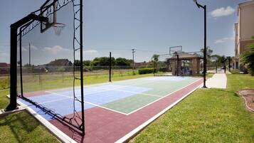A basketball court with a net, a tennis court, and a walking path.