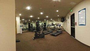 Une salle de sport équipée de tapis de course, d’appareils de musculation et de miroirs.