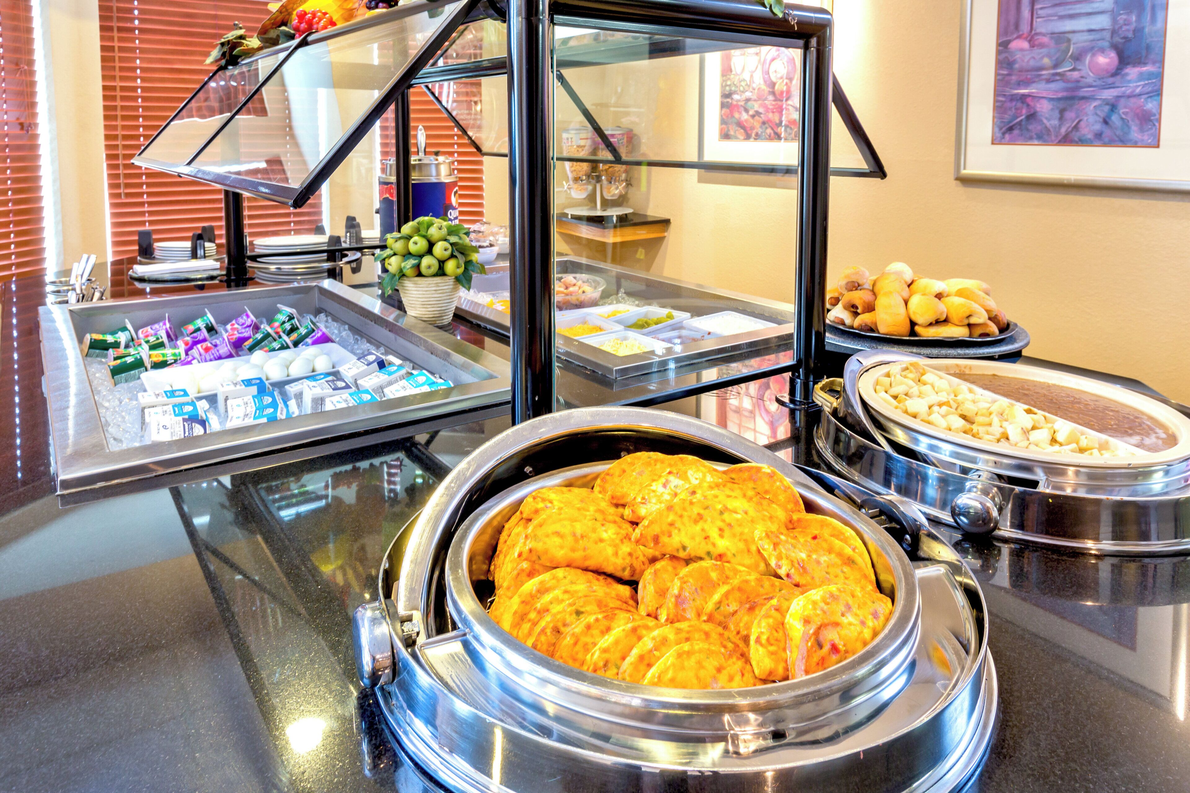 A buffet with various food items, including a large bowl of omelets, trays of pastries, and a fruit display.
