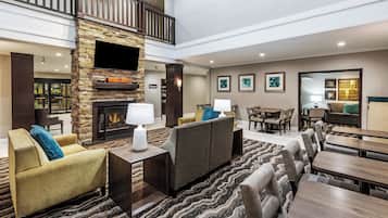 A spacious lobby with a stone fireplace, comfortable seating, and a dining area.
