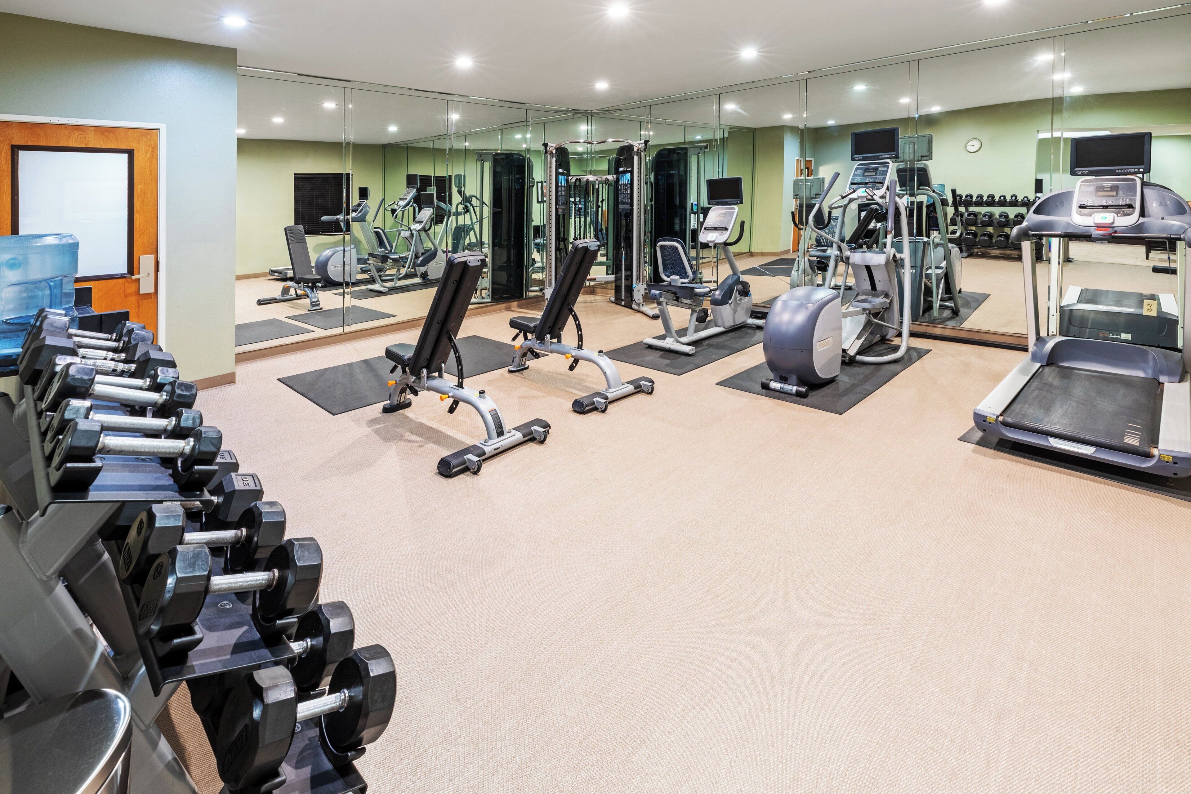 A gym with various exercise equipment, including treadmills, weight machines, and free weights.