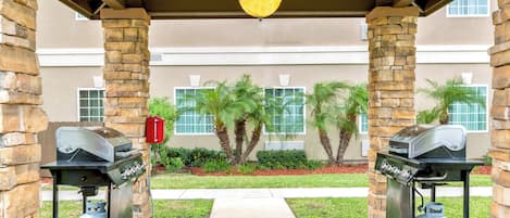 An outdoor patio area with two barbecue grills, gas tanks, and a hanging light fixture.