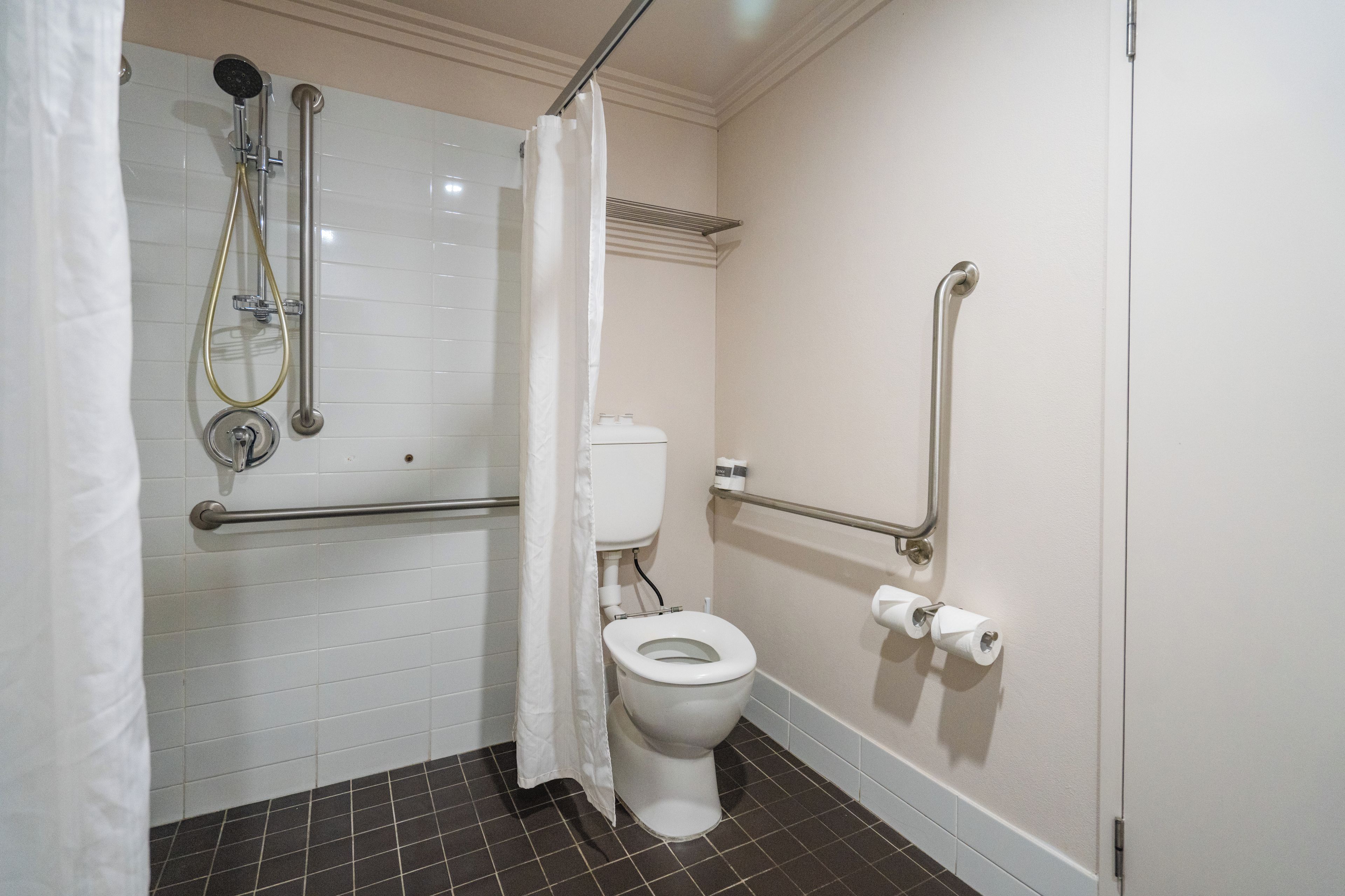 A bathroom with a white toilet, a shower with a glass door, and grab bars.