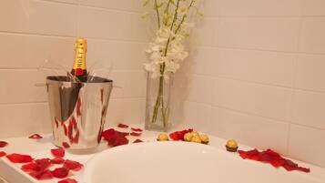 A bathtub with champagne, flowers, and rose petals.