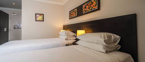 Een hotelkamer met twee bedden, een donker hoofdeinde en twee wanddecoraties.