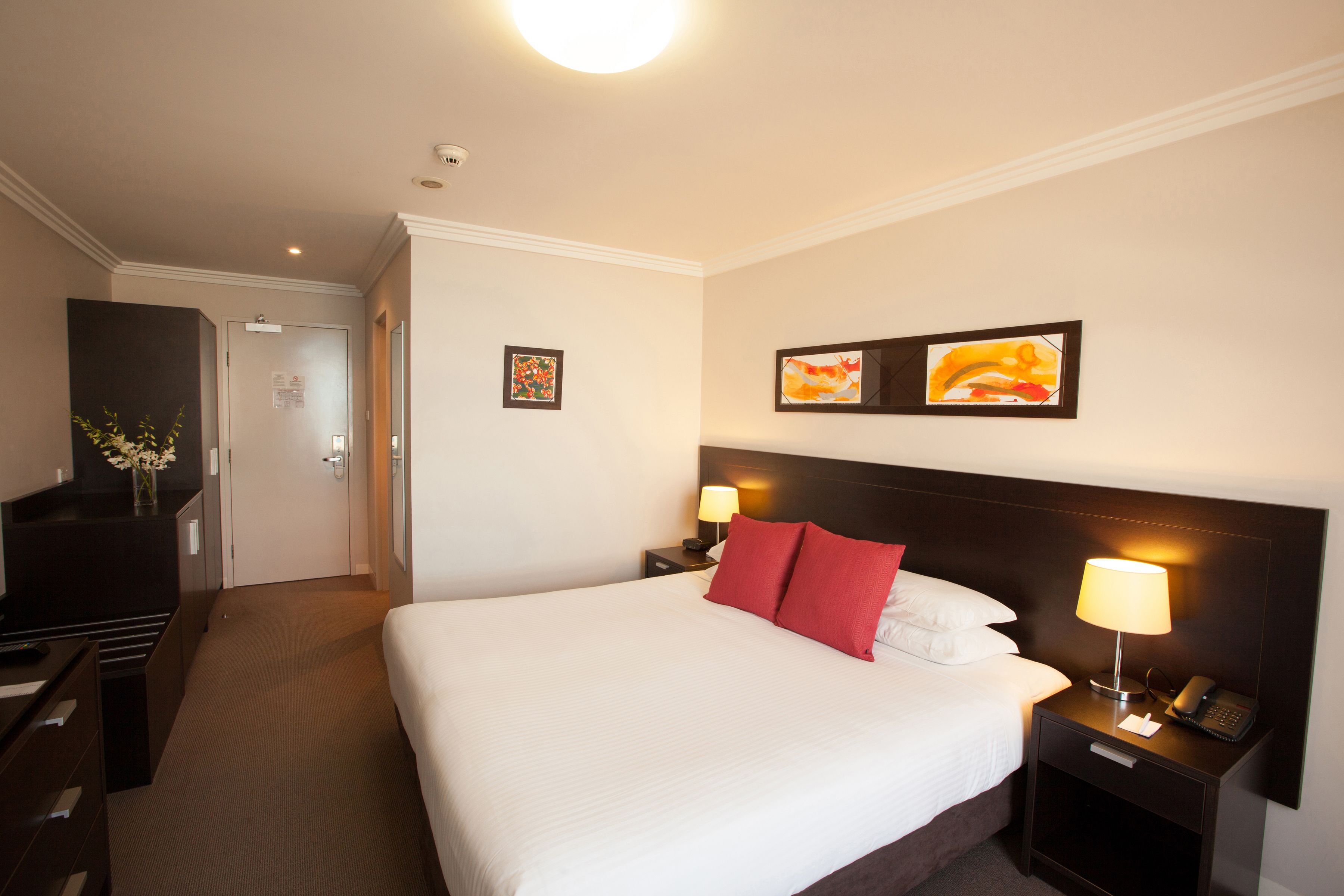Een hotelkamer met een groot bed, twee nachtkastjes met lampen, een bureau met stoel en een dressoir.