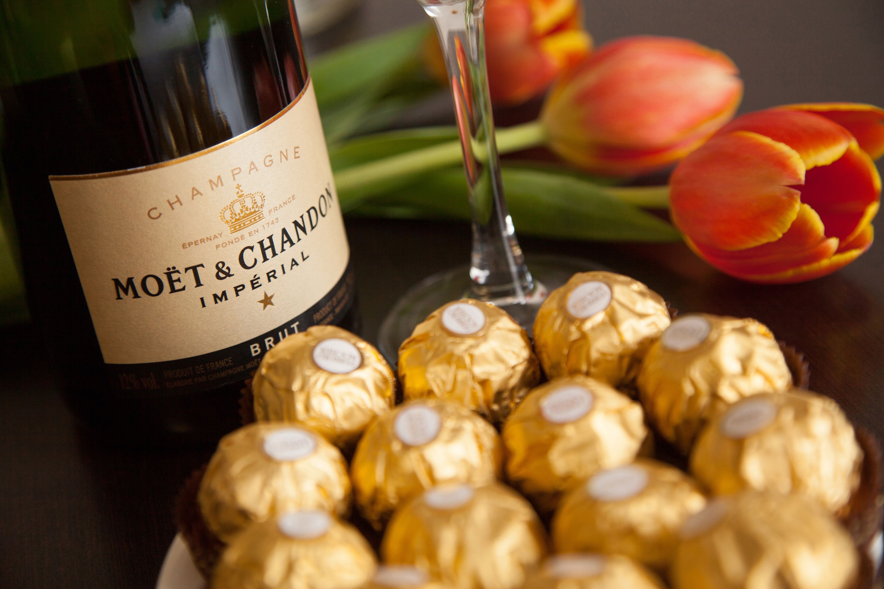 Eine Flasche Moët & Chandon Champagner, ein Glas und mehrere verpackte Pralinen.