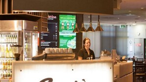 Een receptiegedeelte met een balie met de naam 'Entice', een scherm dat informatie toont en een bar met flessen.