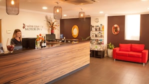 Een receptiezone met een houten receptiebalie, een rode bank en een wandklok.