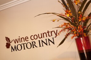 A wall with the text "wine country MOTOR INN" and a decorative plant in a red vase.