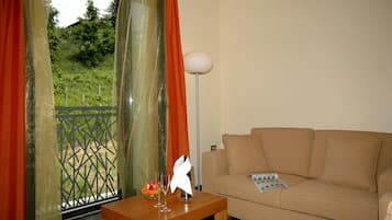 En stue med en beige sofa, et træ sidebord med et magasin, og en gulvlampe.