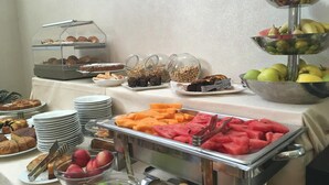 Un buffet proposant une variété de plats, notamment des fruits, des pâtisseries et des desserts.
