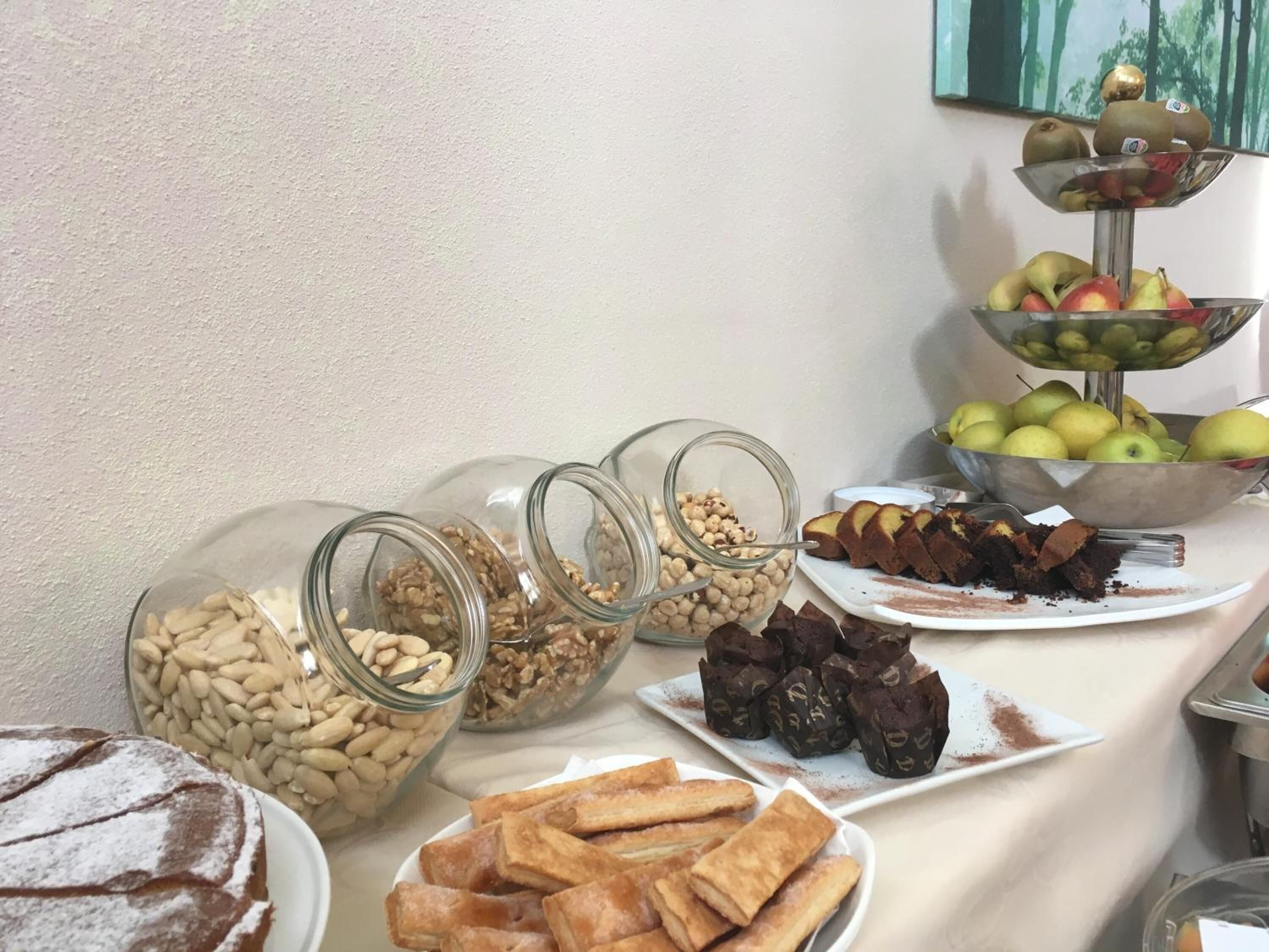 Una mesa de buffet con diversos alimentos, como nueces, pasteles y frutas.