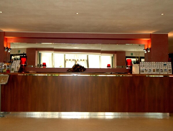 A reception desk with a wooden counter, red lamps, and a window with curtains.