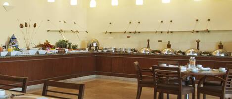 A restaurant with a long counter, multiple tables, and hanging pendant lights.