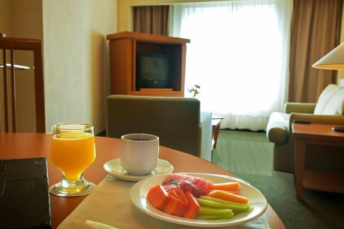A hotel room with a dining table, a television, and a view of the outdoors.