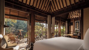 Quarto espaçoso com uma cama grande, teto de madeira e varanda com vista para a floresta.
