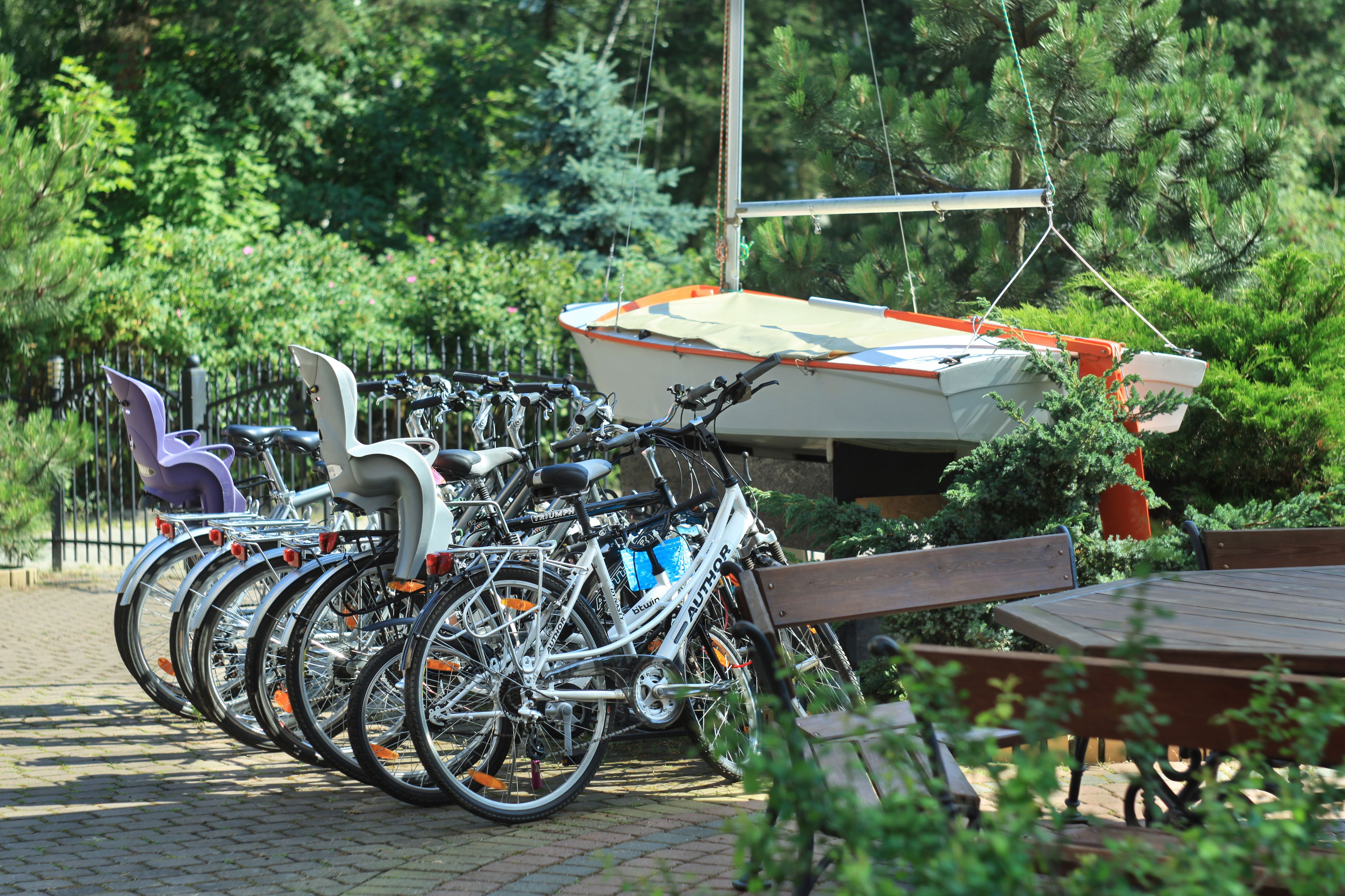 Varias bicicletas estacionadas junto a un banco y una mesa en un jardín.