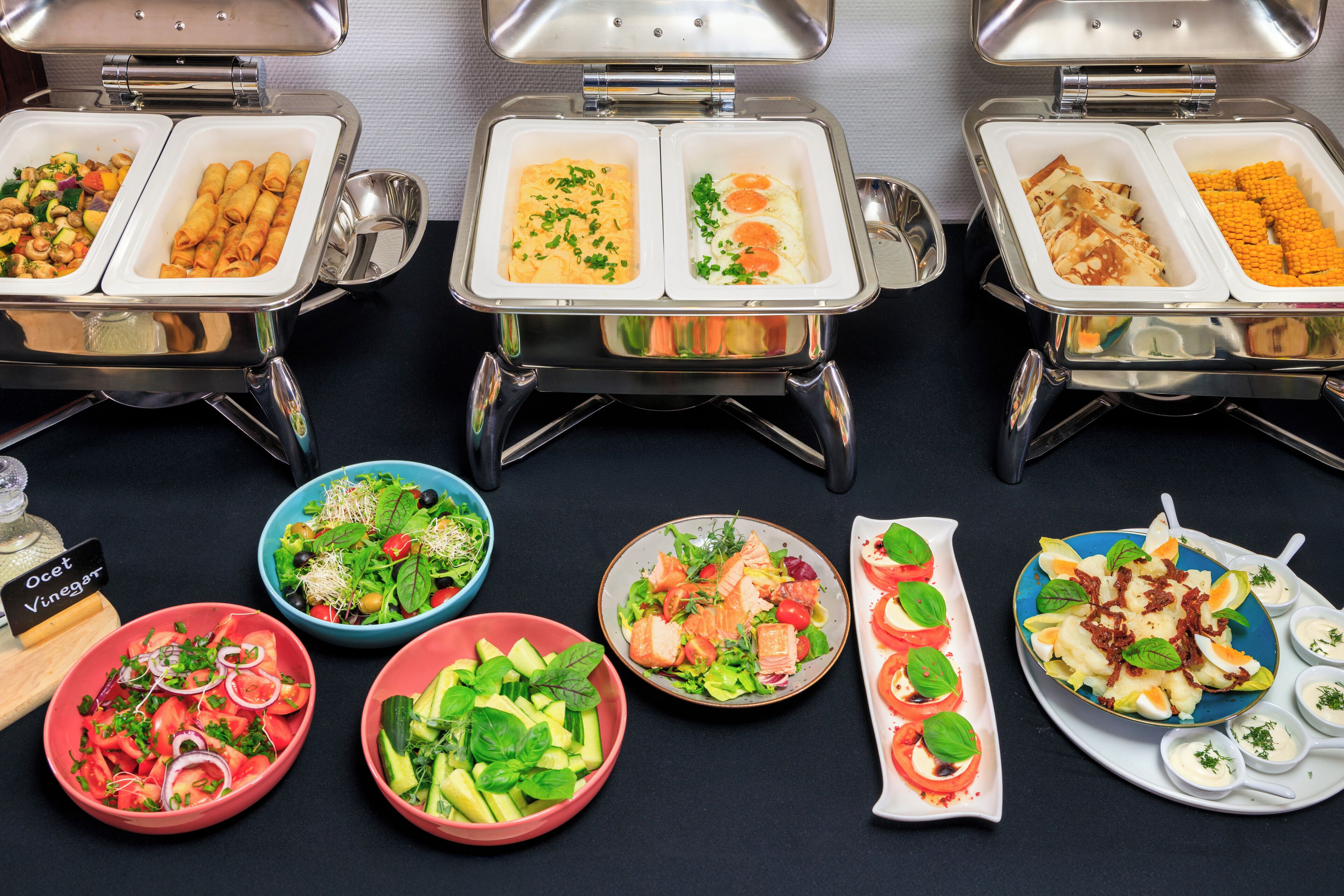 A buffet with various food options including salads, eggs, and rolls.