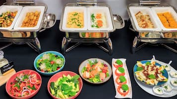 A buffet with various food options including salads, eggs, and rolls.