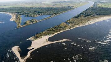 Ett flygbildsbild av ett kustområde med en flod, en sandstrand och skogsområden.
