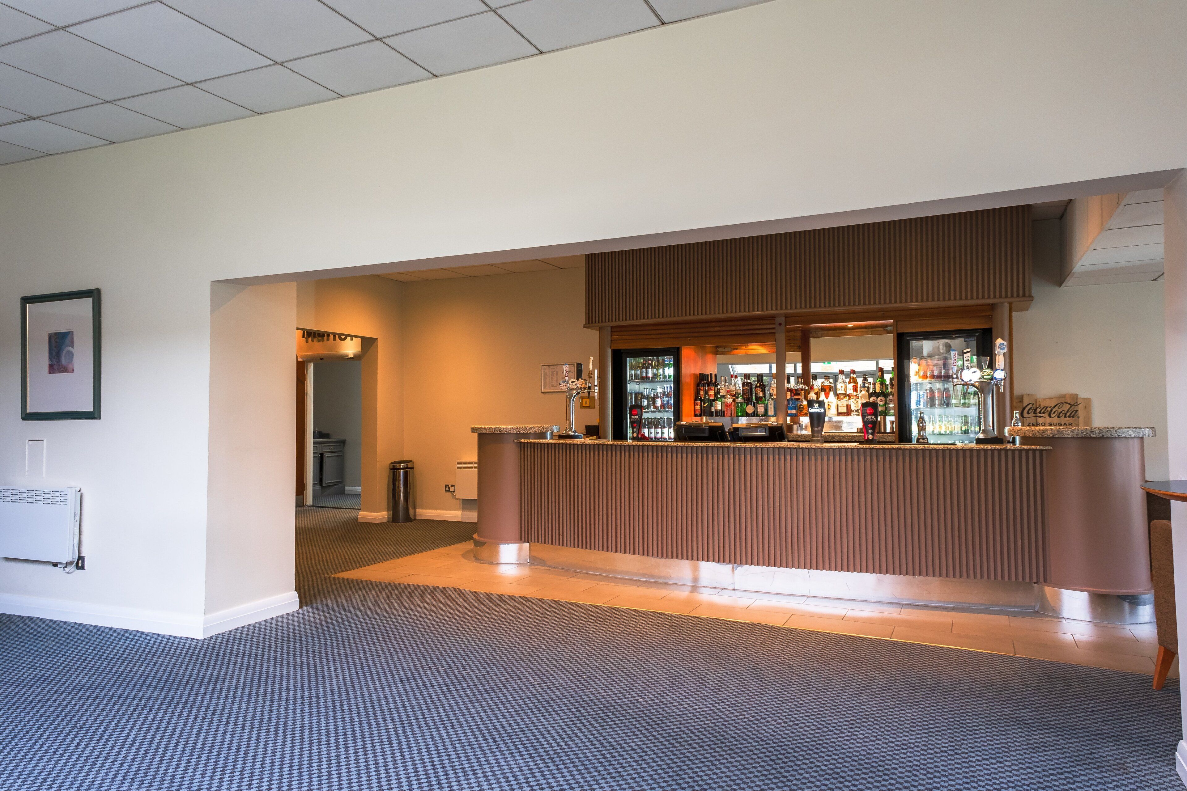A hotel reception area with a counter, a refrigerator, and a Coca-Cola sign.