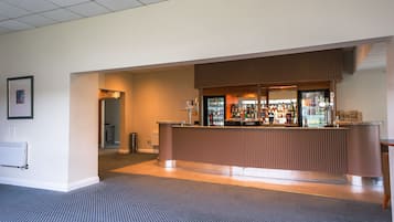 A hotel reception area with a counter, a refrigerator, and a Coca-Cola sign.