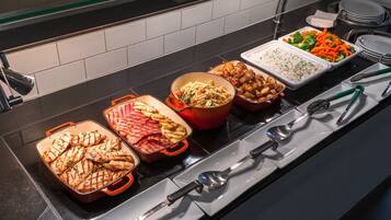 A buffet with various dishes including grilled chicken, pasta, and vegetables.
