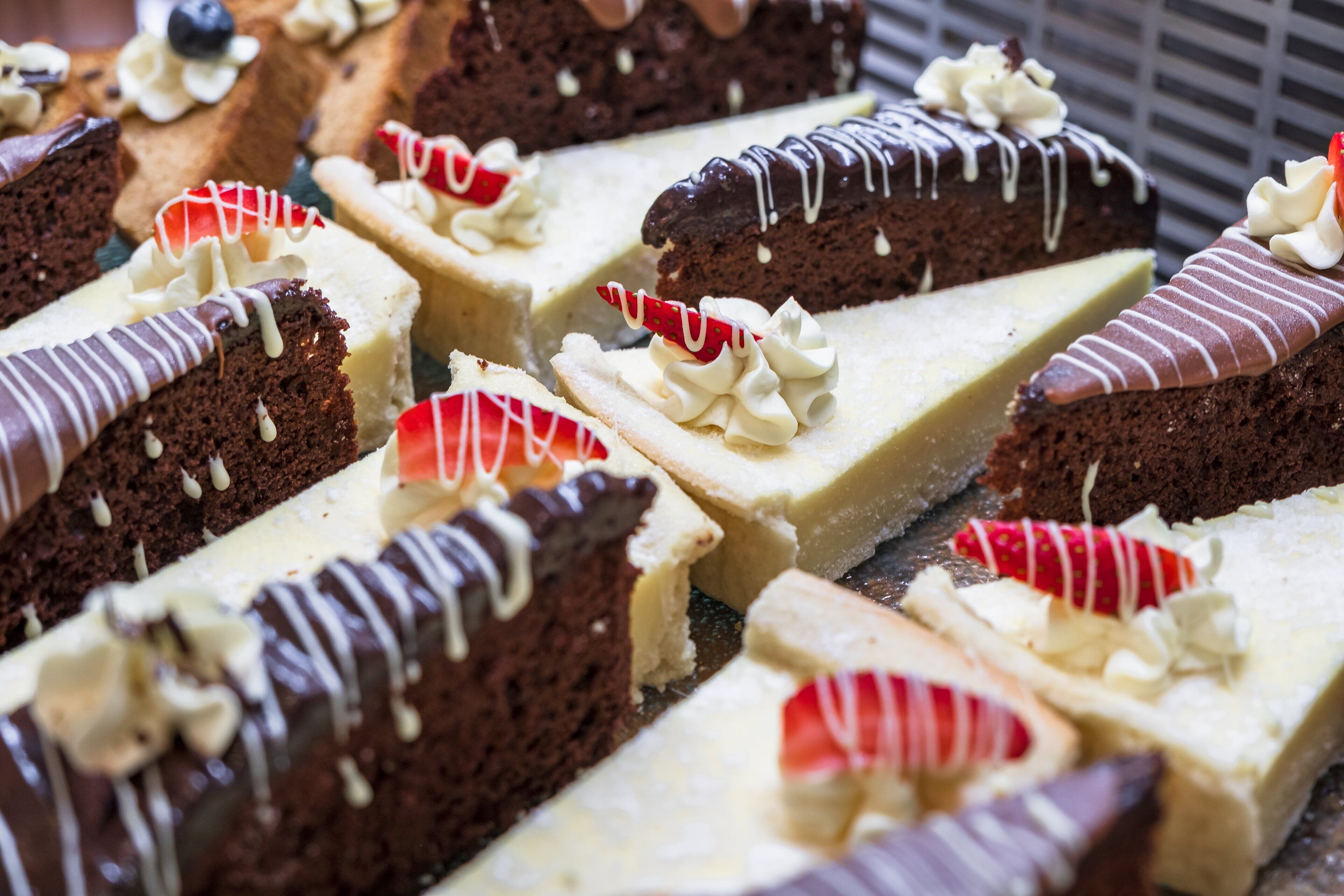 Diverse desserts, waaronder chocolade en stukjes cheesecake, met slagroom en aardbeien.