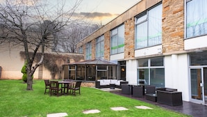 A modern building with a patio area featuring outdoor furniture and a glass enclosure. - Holiday Inn Doncaster A1 M Jct 36 by IHG (Doncaster)