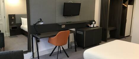 Une chambre d’hôtel équipée d’un lit, d’un bureau, d’une chaise, d’une télévision et d’une armoire.