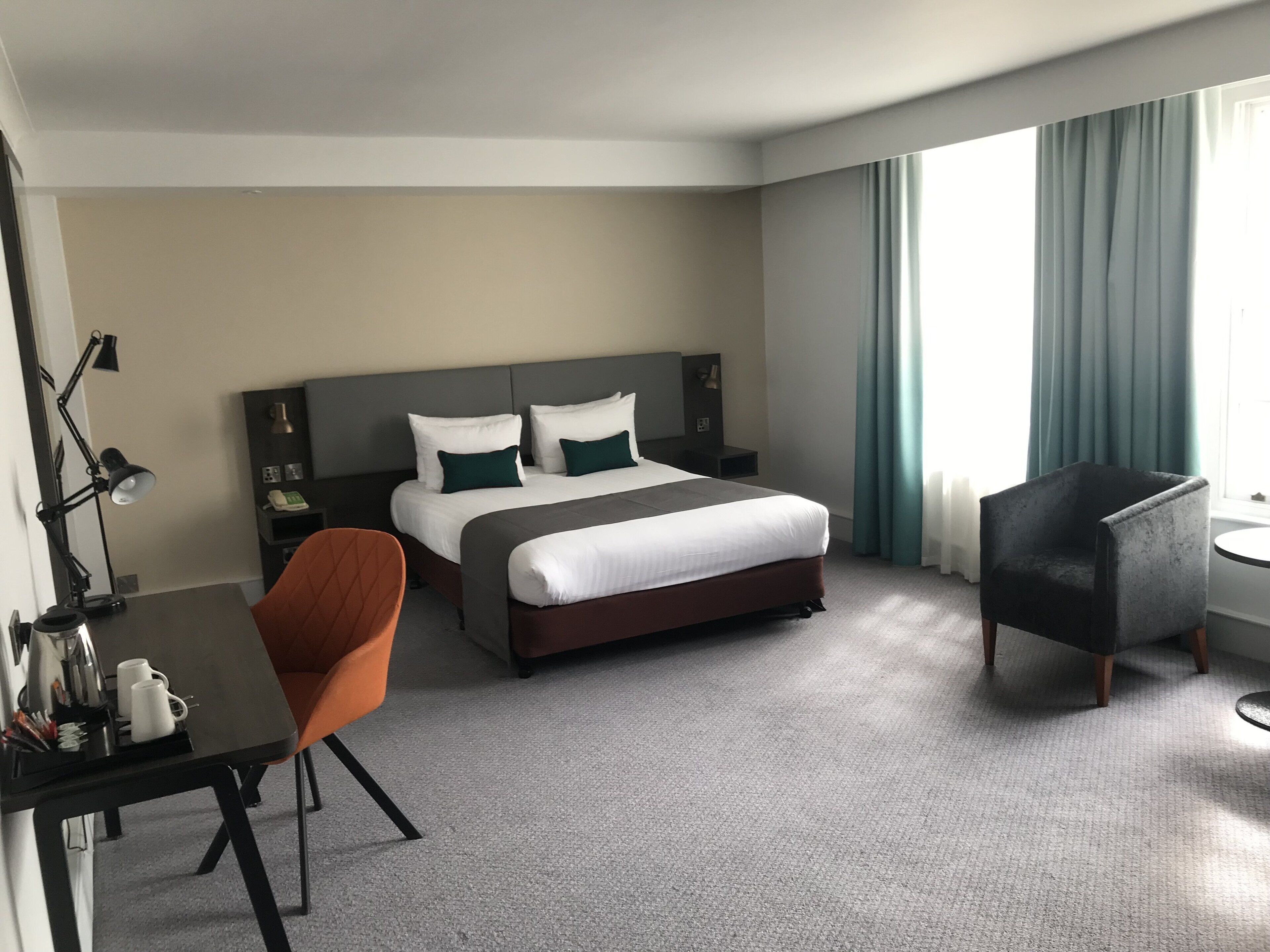 Ett hotellrum med en säng, ett skrivbord, en stol och ett litet bord.