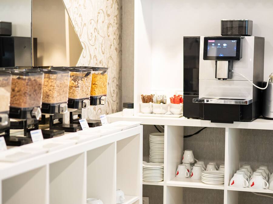 A self-service beverage station with multiple dispensers, a coffee machine, and a selection of cups and saucers.