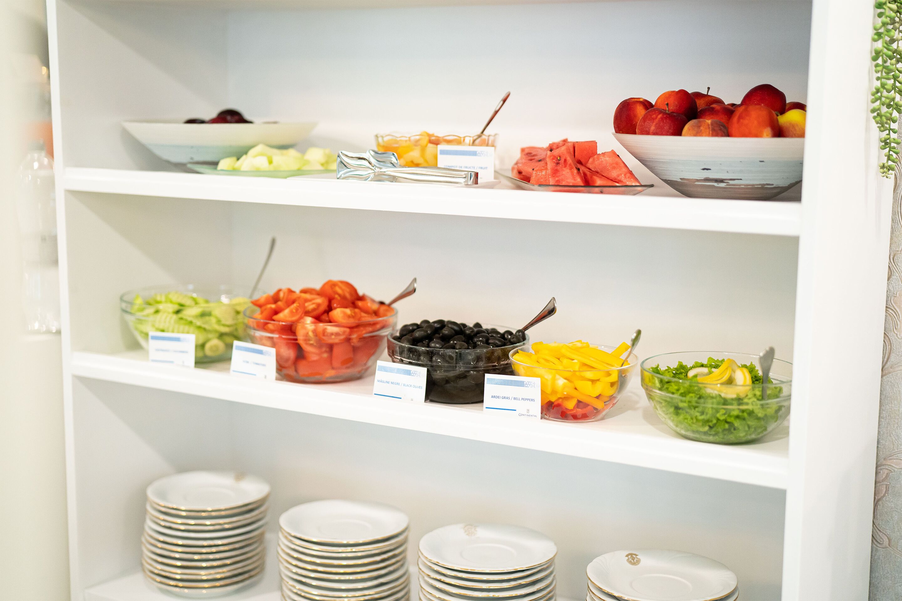 A buffet with various food items and serving utensils on shelves.