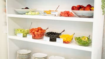 A buffet with various food items and serving utensils on shelves.