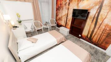 Ein Hotelzimmer mit zwei Betten, einem Fernseher, einem Schreibtisch mit Stühlen und einem großen Wandbild mit Waldmotiv.