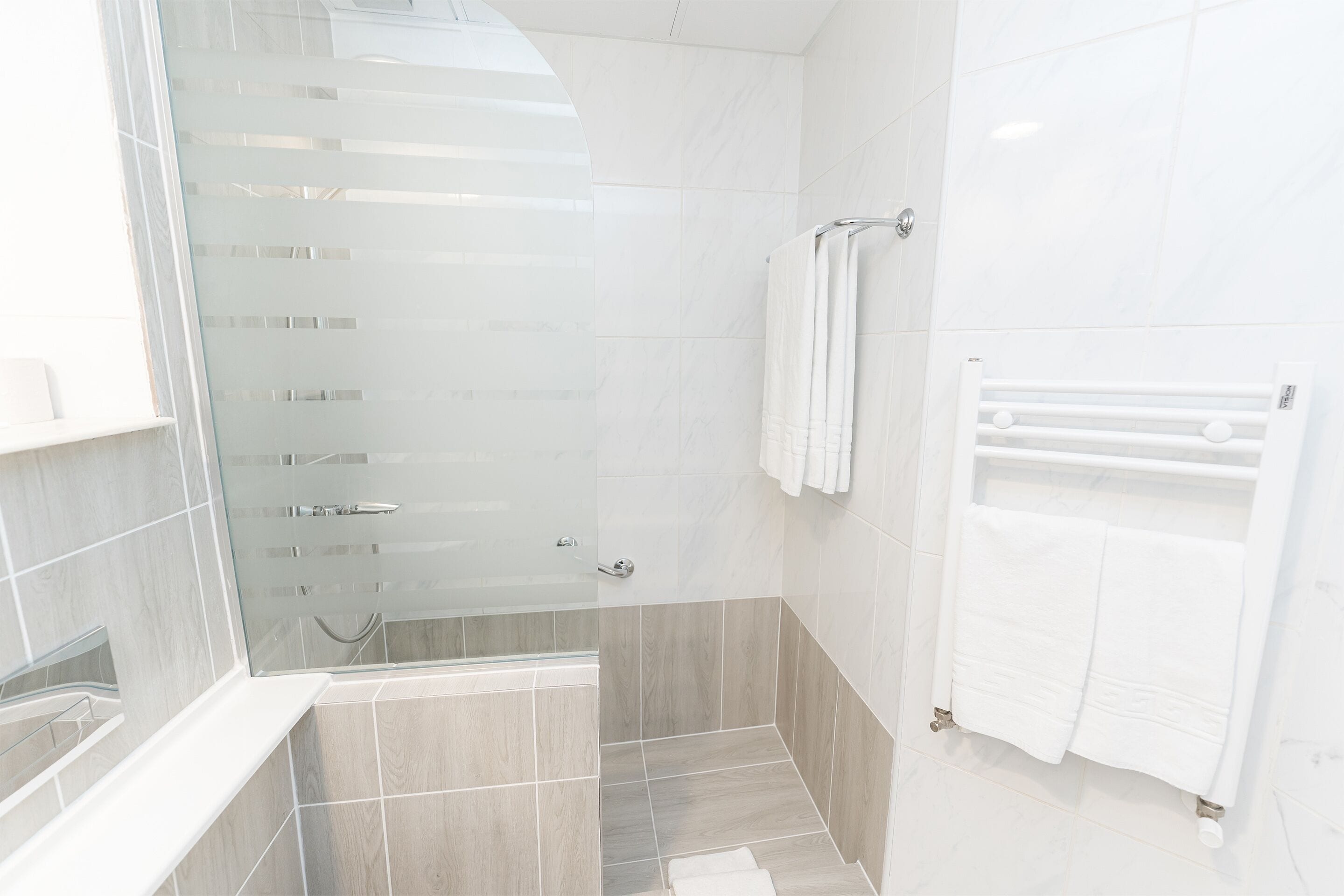 A modern bathroom with a glass shower enclosure, a built-in sink, and a towel rack.