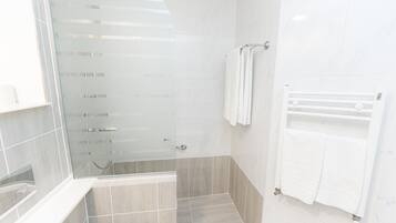 A modern bathroom with a glass shower enclosure, a built-in sink, and a towel rack.